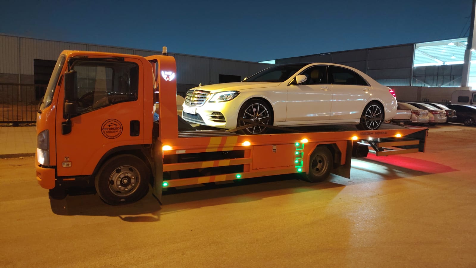 سطحة برتقالية تنقل مرسيدس فاخرة ليلًا